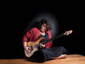 Photo représentant une femme assise en train de jouer de la guitare électrique