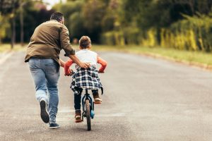 photo d'un père qui apprend à son enfant à faire du vélo