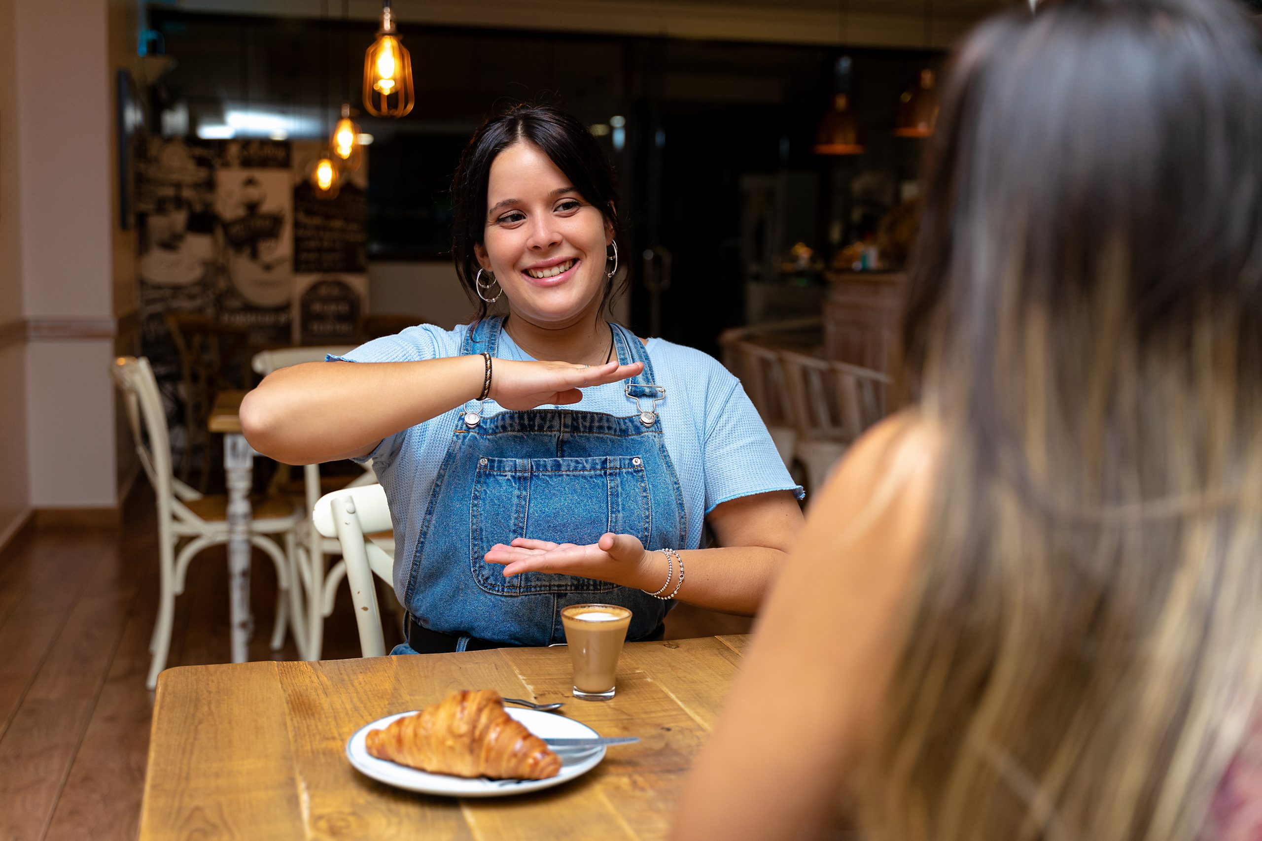 Young woman drinking coffee, making the sign of ability.