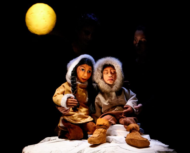 Photo représentant deux marionnettes à taille humaine : deux inuits assis dans la neige