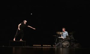 Photo représentant deux hommes sur scène. Un jonglant avec des balles, l'autre jouant de la batterie.