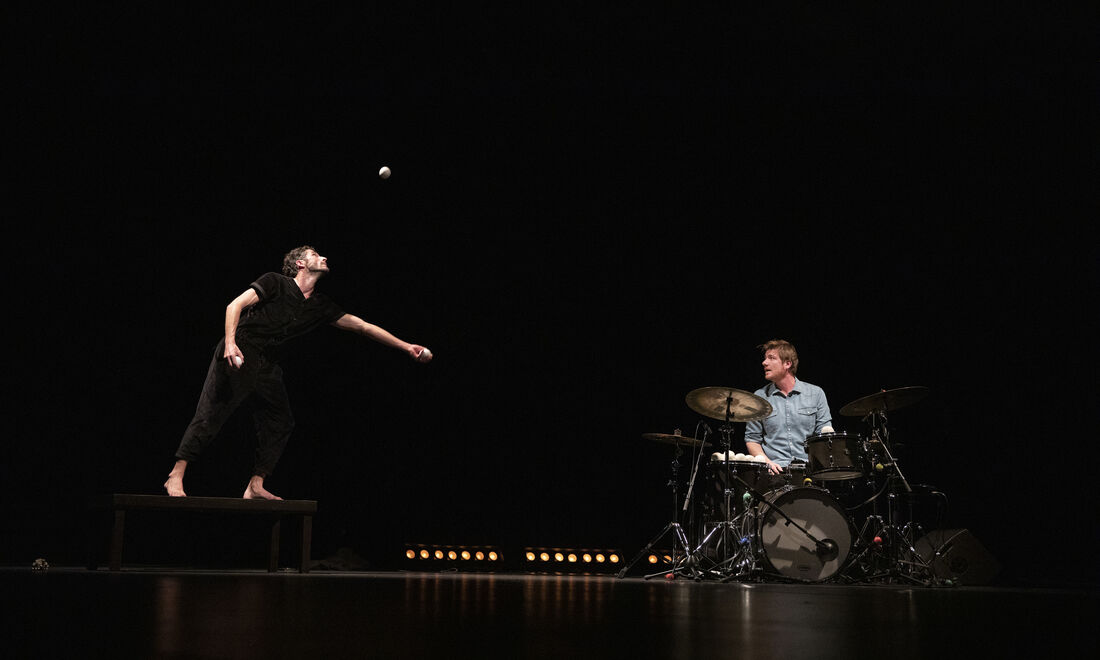 Photo représentant deux hommes sur scène. Un jonglant avec des balles, l'autre jouant de la batterie.