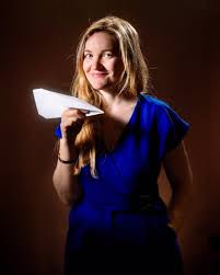 Photo représentant une jeune femme avec un avion en papier dans les mains.