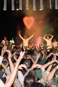 Photo représentant un concert avec des gens en train de danser bras en l'air.
