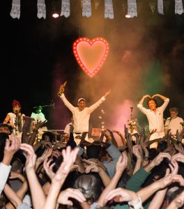 Photo représentant un concert avec des gens en train de danser bras en l'air.