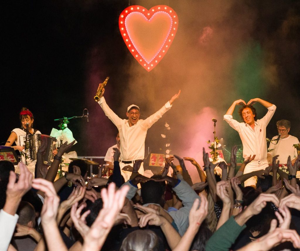 Photo représentant un concert avec des gens en train de danser bras en l'air.