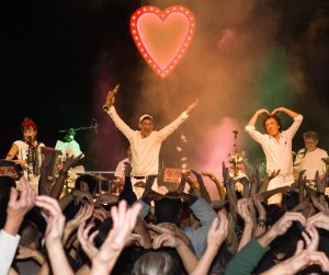 Photo représentant un concert avec des gens en train de danser bras en l'air.