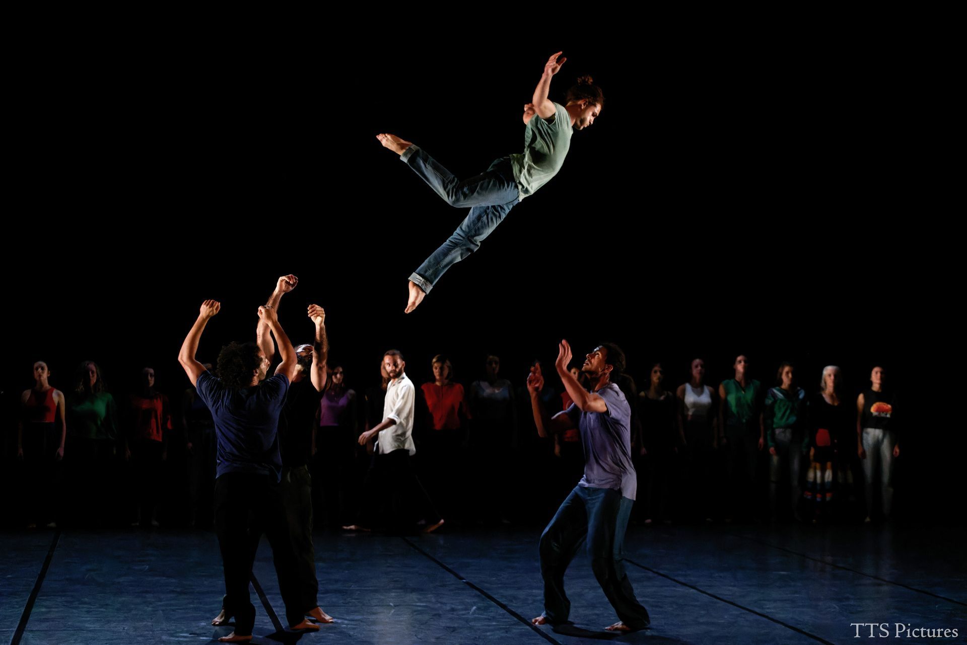 Photo représentant un danseur acrobate en l'air entouré de danseurs pour le rattraper