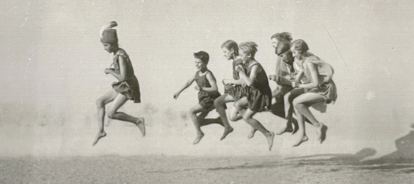 Photo représentant un collage en noir et blanc sur un mur où on voit des enfants en gtrain de sauter et de rire
