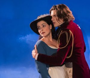 Photo représentant un homme et une femme en costume sur un fond de ciel bleu.