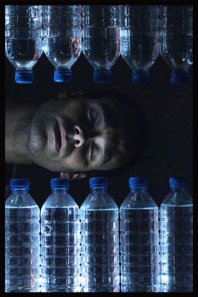 Photo représentant un hommage couché en train de dormir, entouré de bouteilles d'eau