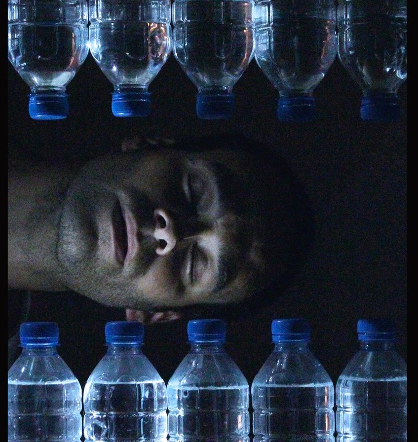 Photo représentant un hommage couché en train de dormir, entouré de bouteilles d'eau