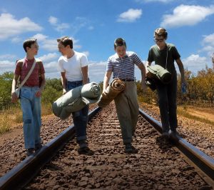 Photo représentant 4 adolescents en train de marcher sur un chemin de fer en discutant